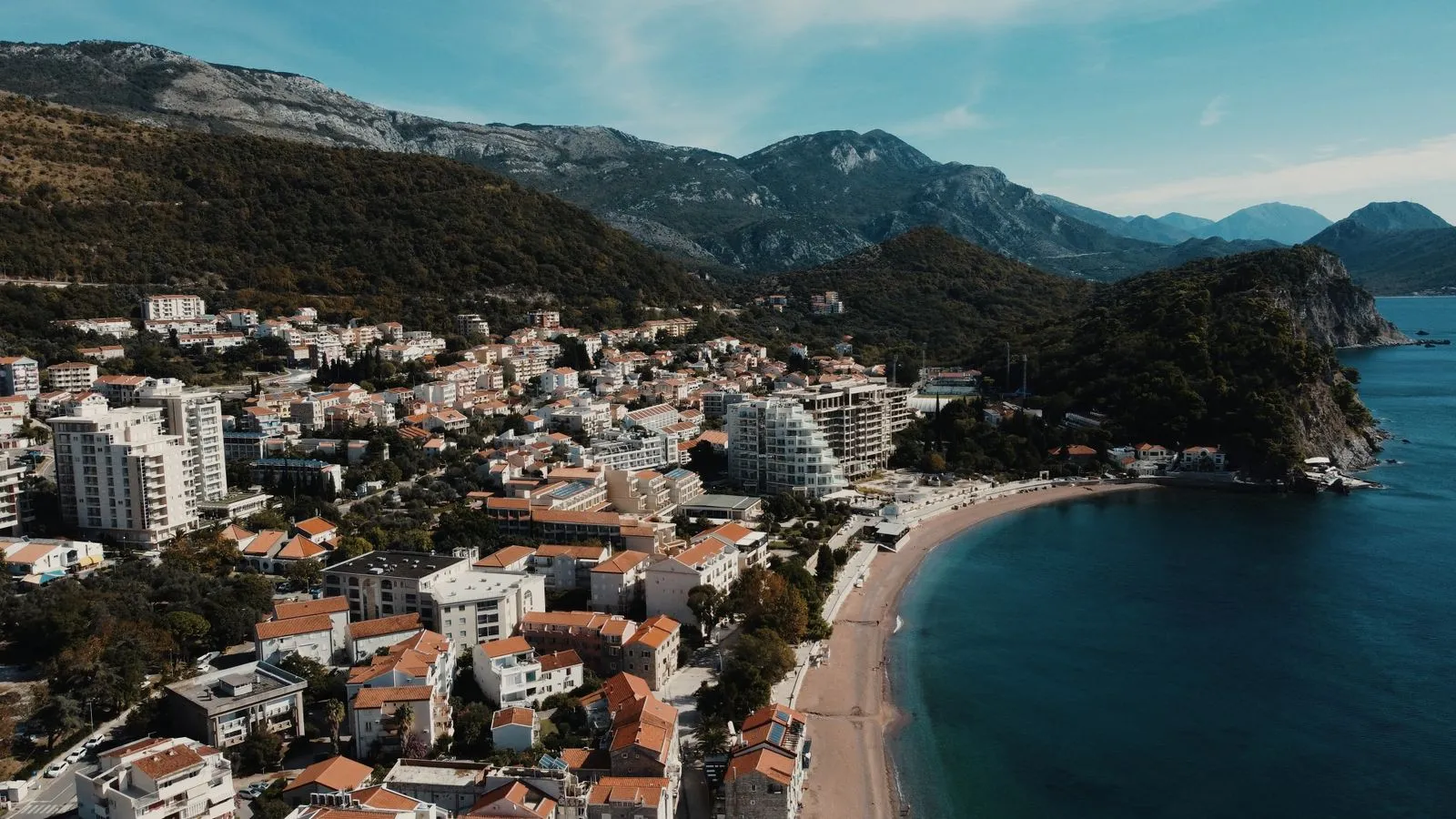 Zachwycający widok z lotu ptaka na Petrovac, Czarnogóra, ukazujący plażę i otaczające góry.